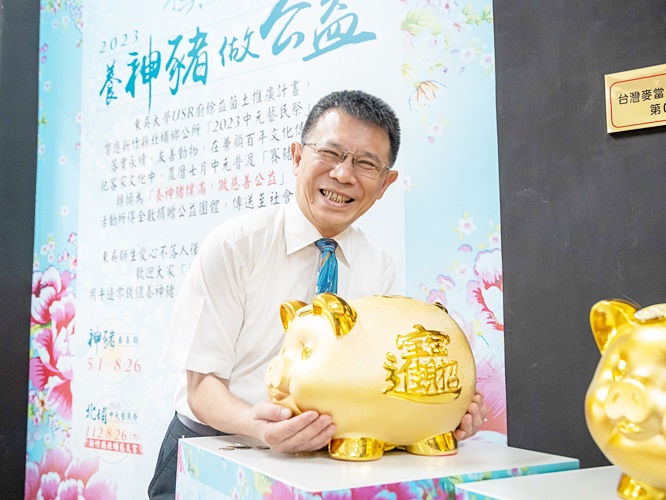 圖片標題:圖二、東吳大學校長潘維大抱金豬撲滿，裏頭是東吳師生沉甸甸的愛心
