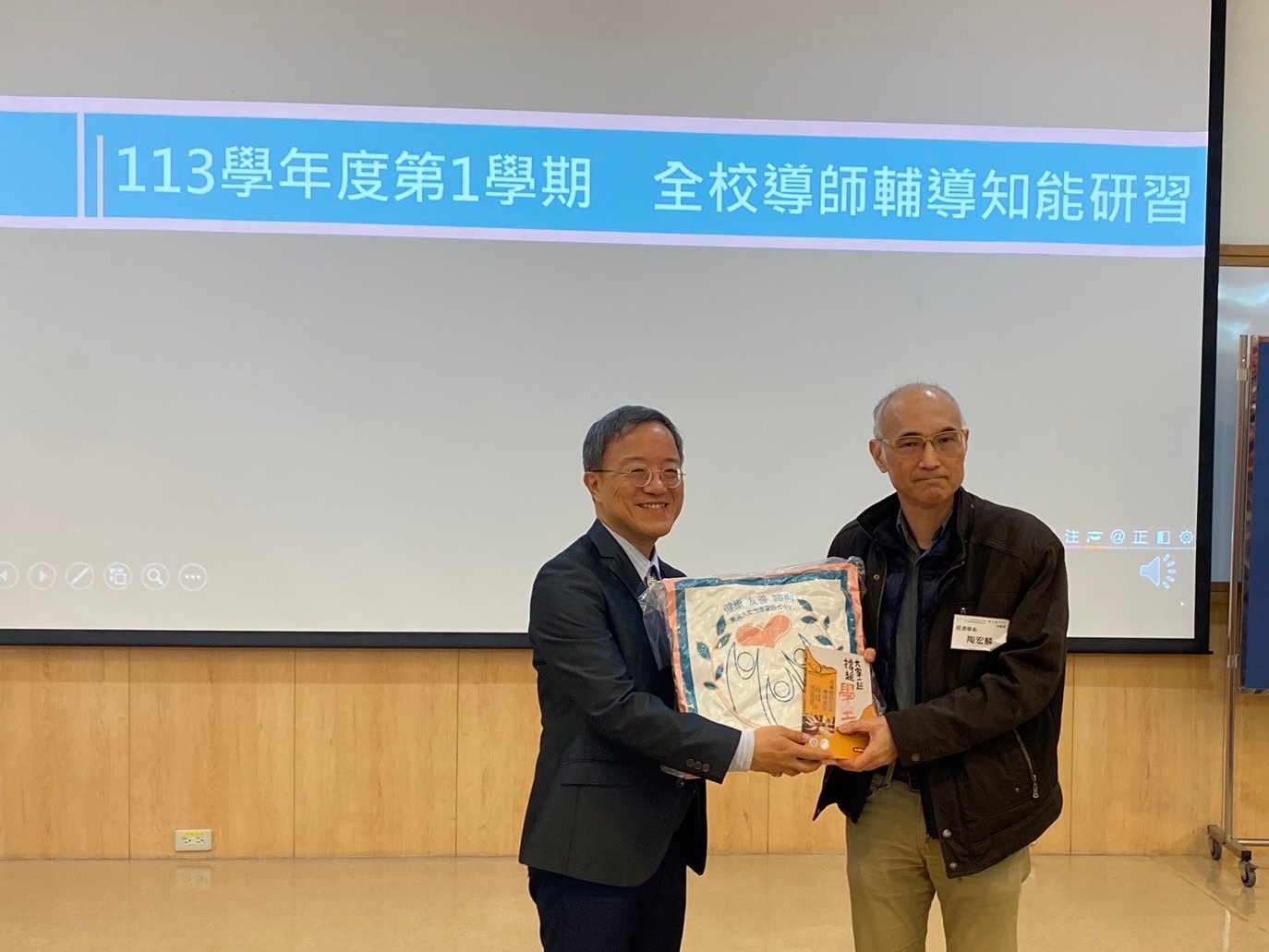 圖片標題:圖三學務長范綱華致贈中心出版的《大專院個案管理實務》書籍予績優導師分享人陶宏麟教授。