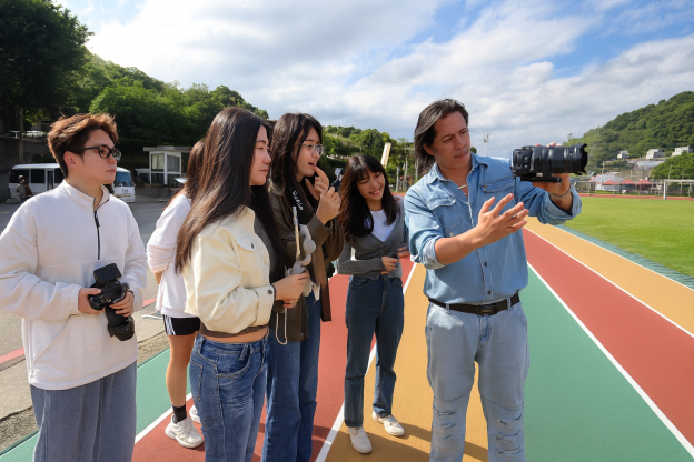 圖片標題:丁名杰導演帶領學生至操場外拍
